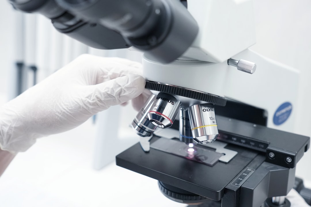 Scientist examining biological samples under microscope in pharmaceutical lab
